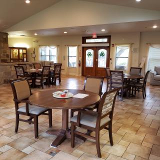 A spacious dining area with wooden tables and chairs, illuminated by soft lighting.