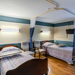 A cozy hospital room featuring two beds, comfortable seating, and soft lighting.