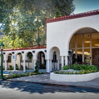 A building with arched entrances surrounded by trees.
