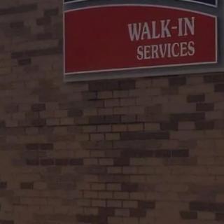 A sign on a brick wall indicating walk-in services.