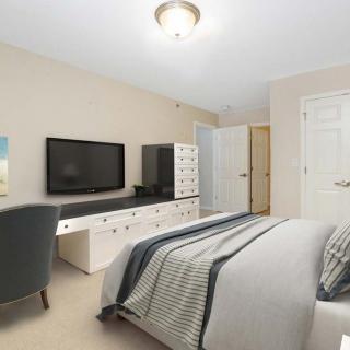 A modern bedroom with a comfortable bed, a television on a dresser, and stylish decor.