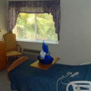 A hospital room with a bed, chair, and a window with curtains.