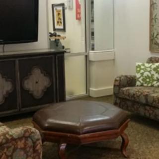 A cozy living room with a large ottoman, sofas, and a television.