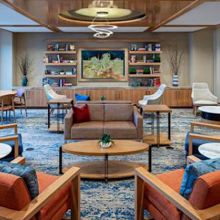 A stylish and inviting lounge area featuring modern furniture and a cozy bookshelf backdrop.