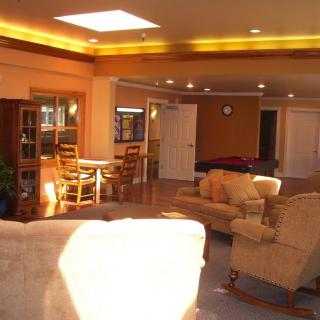 A cozy living room with comfortable seating and a dining area, illuminated by ceiling lights.