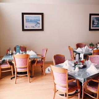 An inviting restaurant dining area with neatly arranged tables and chairs, featuring framed artwork on the walls.