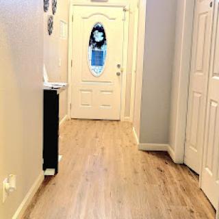A well-lit hallway featuring a stylish front door and polished flooring.
