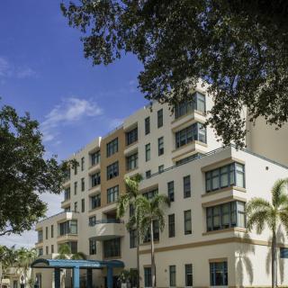 A modern residential building surrounded by palm trees on a sunny day.