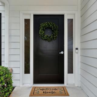 A welcoming front door adorned with a wreath and a 'Home Sweet Home' doormat.