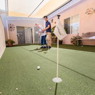 A man practicing his putting skills on an indoor golf green.