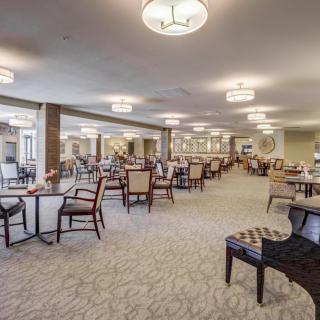 A spacious dining area with neatly arranged tables and chairs, illuminated by modern ceiling lights.