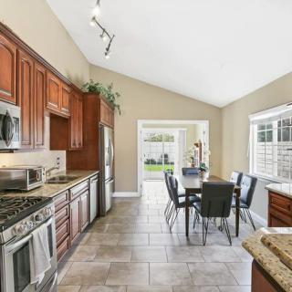 A modern kitchen with stainless steel appliances and a dining area leading to the backyard.