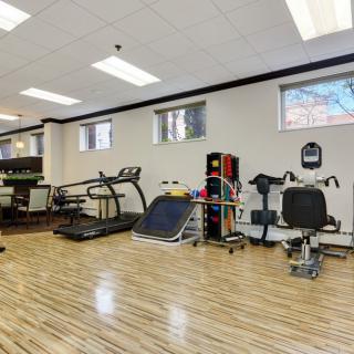 A well-equipped gym with various exercise machines and a wooden floor.