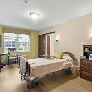 A well-lit hospital room featuring a single bed and comfortable furnishings.