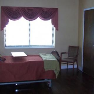 A simple hospital room with a bed, chair, and window.