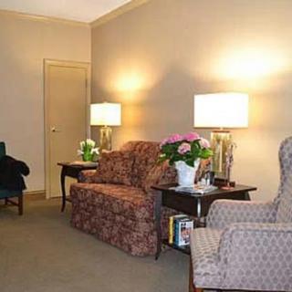 A cozy living room with classic furniture, featuring a sofa, armchair, and lamps on side tables.