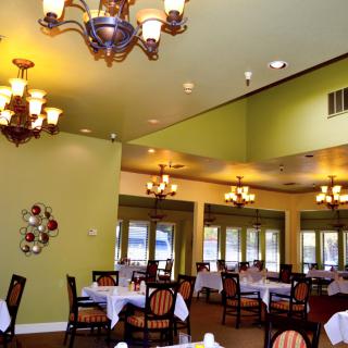 A spacious dining room with elegant chandeliers and neatly arranged tables and chairs.