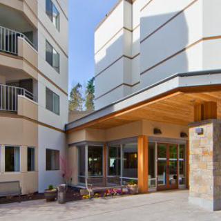 A modern building with balconies and an inviting entrance featuring outdoor seating.