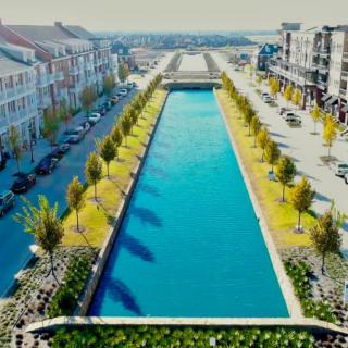 An urban canal flanked by buildings and trees on a sunny day.