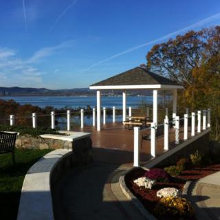 A picturesque waterfront gazebo overlooking a serene lake under a clear blue sky.