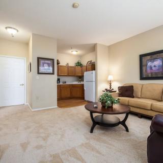 A cozy apartment living room with a sofa, coffee table, and a kitchenette in the background.