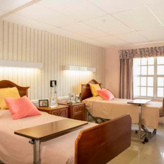 A bright and well-organized hospital room with two beds, featuring warm lighting and cozy decor.