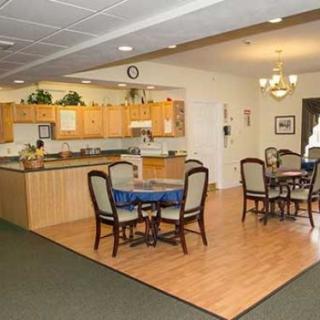 A spacious kitchen and dining area with wooden floors, tables, and chairs under a chandelier.