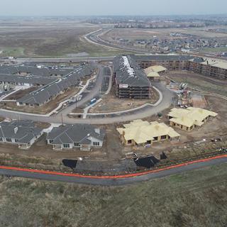 An aerial view of a residential construction site surrounded by existing suburban housing.