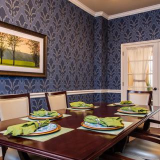 A beautifully decorated dining room with elegant blue wallpaper and a well-set dinner table.