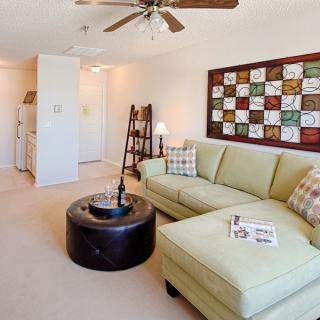 A cozy living room with a light green sofa, a round coffee table, and colorful artwork on the wall.