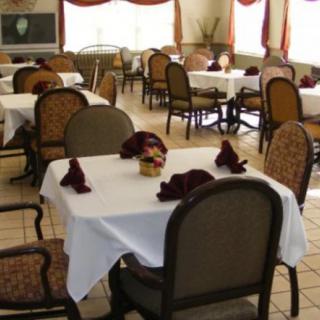 An elegantly set dining room with tables covered in white tablecloths and neatly arranged chairs.