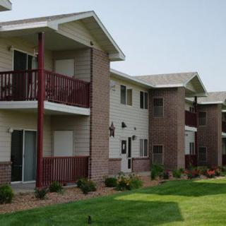 A view of a residential apartment building with balconies and a well-maintained lawn.