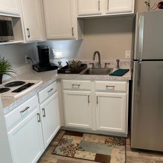 A compact kitchen with white cabinets, a stainless steel refrigerator, and various appliances.