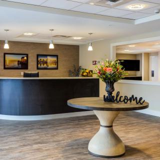 A modern lobby reception area featuring a welcome sign and floral arrangement.