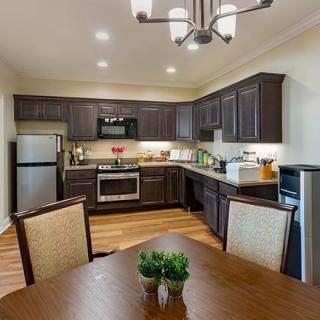 A modern kitchen with dark wooden cabinets, stainless steel appliances, and a cozy dining area.