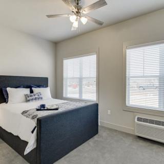 A minimalist bedroom with a bed, two windows, and a ceiling fan.