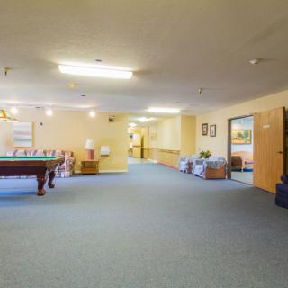 A spacious recreational room featuring a pool table and comfortable seating areas.