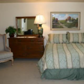 A cozy bedroom with a bed, dresser, and chair.