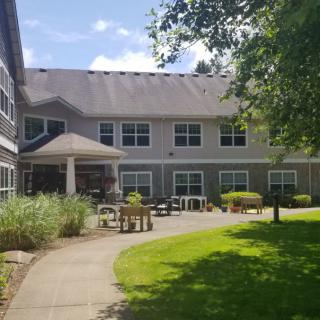 A sunny view of a two-story building with a garden and pathway.