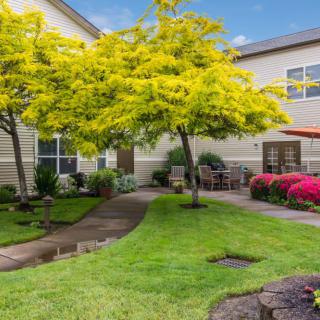 A beautifully landscaped garden with lush greenery, colorful flowers, and a winding pathway.