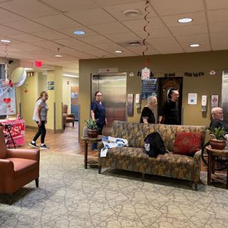 A waiting area with people near elevators and cozy seating.