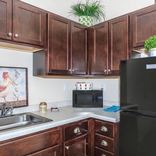 A modern kitchen with dark wood cabinets, a countertop, and appliances.