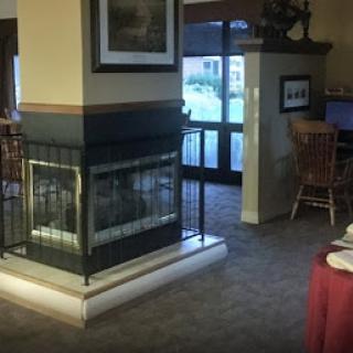 A cozy lounge space featuring a fireplace, with dining tables set nearby.