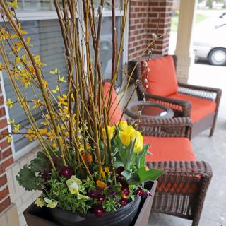 A cozy porch with wicker chairs and a vibrant flower arrangement in a planter.