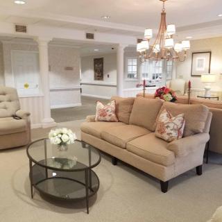 A cozy and elegantly decorated living room with a sofa, glass coffee table, and chandelier.