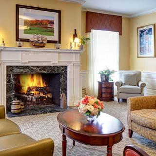 A cozy living room with a lit fireplace, elegant furniture, and tasteful decor.