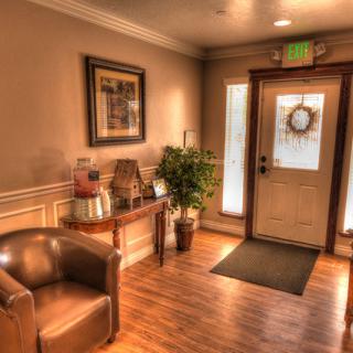 A cozy interior of a lobby with a leather chair, wooden floors, and soft lighting.