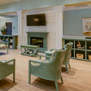 A cozy living room with pastel-colored furniture, featuring a fireplace and a mounted television.