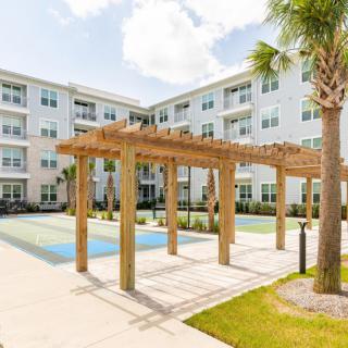 A modern apartment complex featuring a pergola and pool area surrounded by landscaped greenery.
