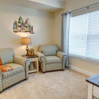 A cozy living room with two patterned armchairs, a lamp, and a window covered by curtains.
